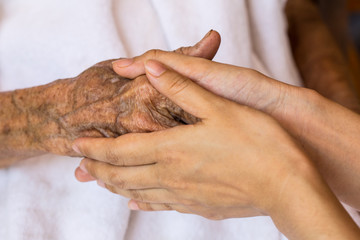 Hand of woman touching senior woman in clinic.