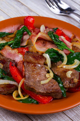 Fried meat, bacon, red paprika pepper and spinach plate