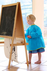 Obraz premium Cute preschooler girl drawing or painting indoors