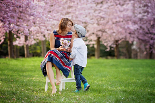 Beautiful kid and mom in spring park, flower and present. Mother