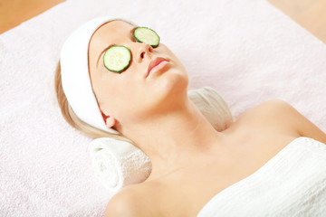 Young woman with cucumber mask on her eyes