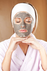 Young woman with clay skin mask on her face