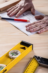 mens hands on blueprint with tools