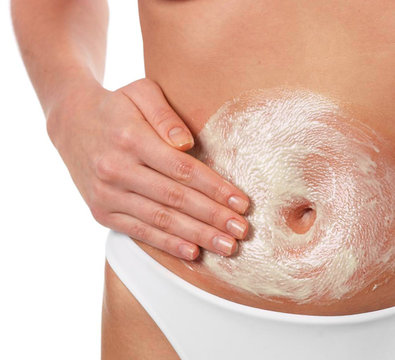 Donna che applica crema di bellezza sulla pancia