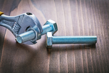 two bolts and adjustable wrench on old wooden board