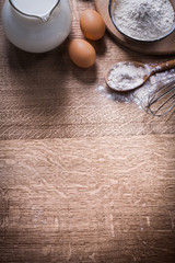 two eggs pitcher milk bowl and sppon with flour corolla organize