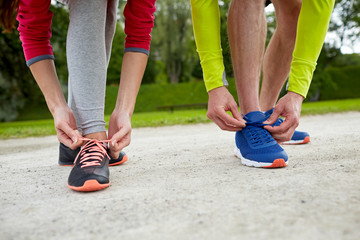 close up of couple tying shoelaces outdoors