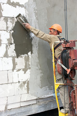 Construction  worker plastering multi storey building wall