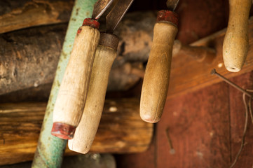 Set of various old rusty sickles, hanging in a shed