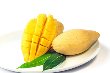 Mango fruit with leaves on a white dish.