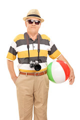 Mature tourist holding a beach ball