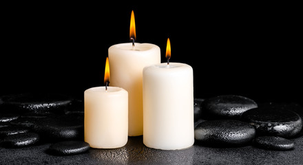 Fototapeta na wymiar spa concept of white candles on zen basalt stones with drops, pa