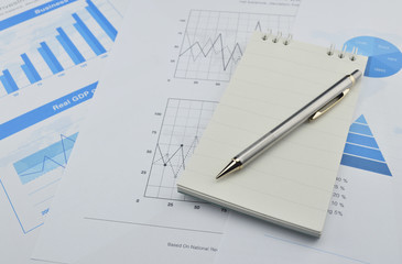 Naklejka na ściany i meble Pen and notebook on financial chart and graph