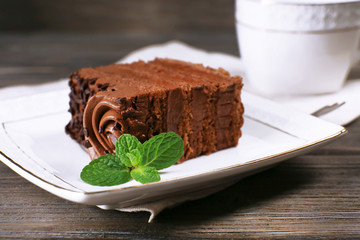 Tasty piece of chocolate cake with mint on wooden table background