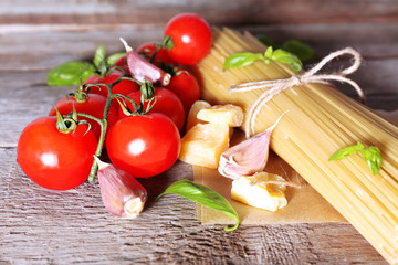 Pasta with cherry tomatoes and other ingredients on wooden table background