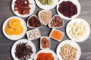 Different products on saucers on wooden table, top view