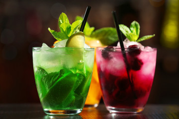 Glasses of cocktails on bar background