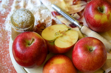Sugar shaker, apples and peel knife on wooden chopping board