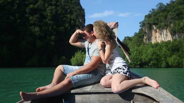blonde girl speaks with handsome guy sitting on longtail boat	