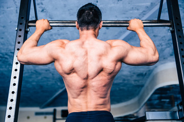 Back view portrait of a muscular man pulling up