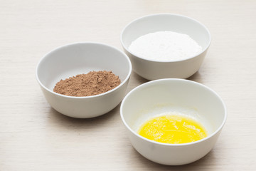 Bowl with home eggs, bowl with cocoa and bowl with milk