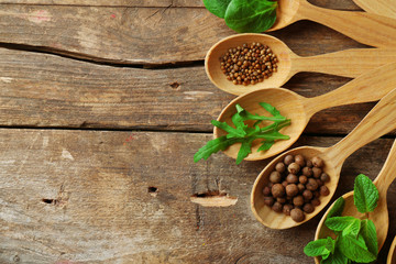 Wooden spoons with fresh herbs and spices on wooden background