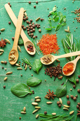 Wooden spoons with fresh herbs and spices on wooden background