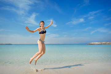Fototapeta na wymiar bright picture of happy jumping woman on the beach