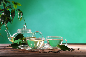 Cups of green tea on table on green background