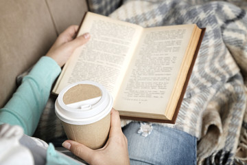 Naklejka premium Young woman reading book, close-up, on home interior background