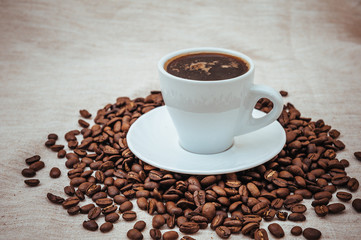 Cup of coffee and roasted beans on beige background