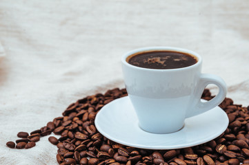 Cup of coffee and roasted beans on beige background