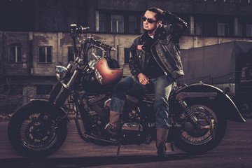 Naklejka na ściany i meble Biker and his bobber style motorcycle on a city streets