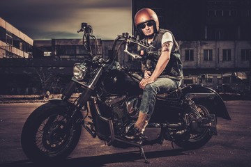Fototapeta na wymiar Biker and his bobber style motorcycle on a city streets