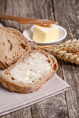 Tasty bread with wheat on wooden background.