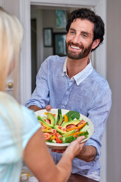 woman handing salad to man