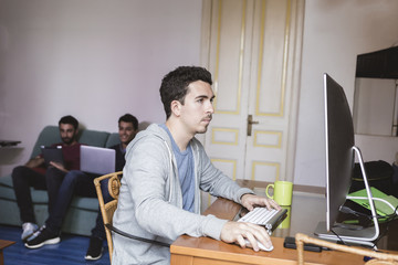 Young man with Computer near the windows at student apartment