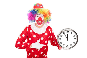 Young male clown holding a big wall clock