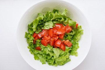 Healthy green salad, tomatoes in white bowl