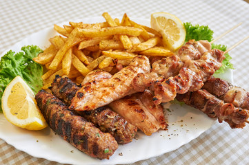 Assort of Grilled sausages with fries and vegetables, barbecue