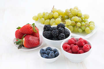 Fresh garden berries and grapes on a white wooden table