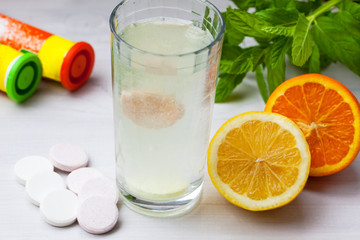 Multivitamin tablet in water with lemon and orange
