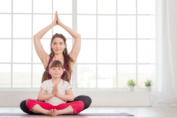 Young mother and daughter sitting in lotus position