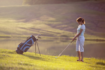 Young female playing golf near the lake.