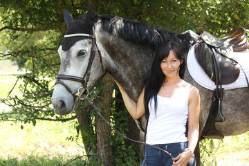 Portrait of beautiful woman and gray horse in garden