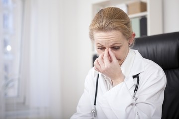 Stressed Female Doctor Holding her Nose Bridge