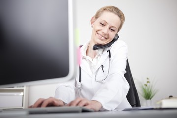 Happy Woman Doctor on Phone Using Computer