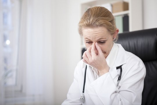 Stressed Female Doctor Holding Her Nose Bridge