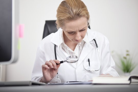 Female Doctor Reading Using Magnifying Glass