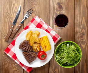 Steak with grilled potato, corn, salad and red wine